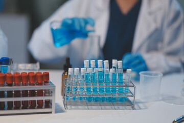 Group of dedicated scientist conduct chemical experiment in medical laboratory, carefully drop precise amount of liquid from pipette into test tube for vaccine drug or antibiotic development. Neoteric