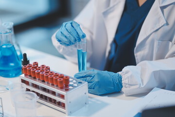 Group of dedicated scientist conduct chemical experiment in medical laboratory, carefully drop precise amount of liquid from pipette into test tube for vaccine drug or antibiotic development. Neoteric