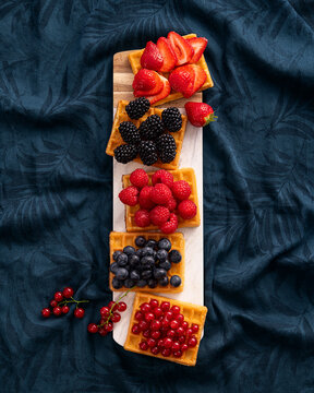 Waffles with fresh summer berries on a dark blue floral background