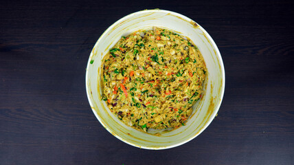 Top View of Mixed Vegetable Pakora Batter in a White Bowl on Dark Wooden Surface - Indian Street Food Preparation