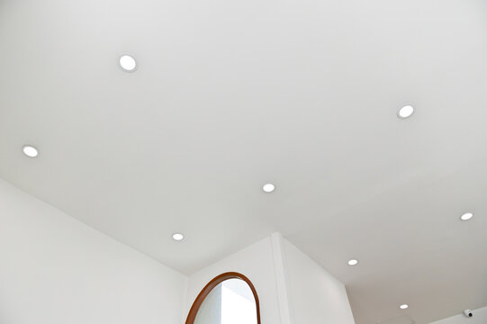 Modern ceiling with recessed lighting and a large arched window.