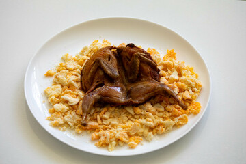 Quail prepared on a plate with pasta and egg crumbs