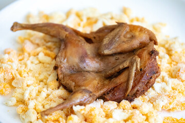 Quail prepared on a plate with pasta and egg crumbs