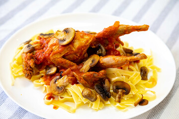 Quail prepared on a plate with pasta and egg crumbs