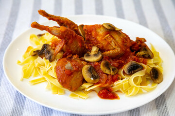 Quail prepared on a plate with pasta and egg crumbs