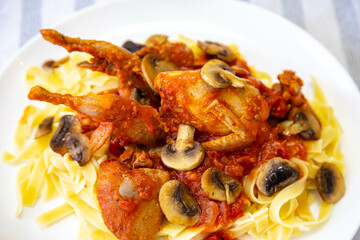 Quail prepared on a plate with pasta and egg crumbs