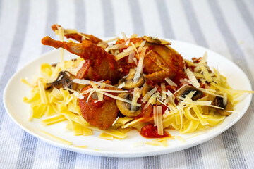 Quail prepared on a plate with pasta and egg crumbs