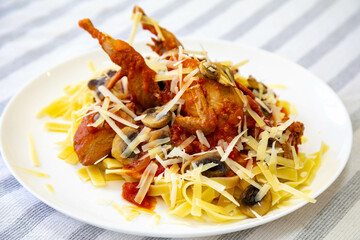 Quail prepared on a plate with pasta and egg crumbs