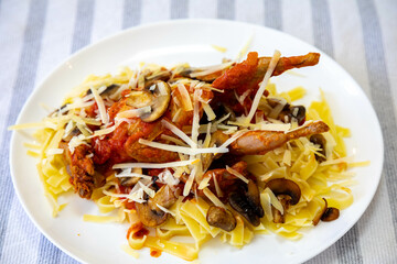 Quail prepared on a plate with pasta and egg crumbs