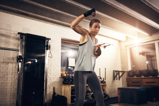 Fit mature woman lifting dumbbells at a boxing gym