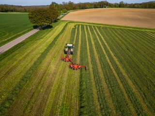 Aerial drone shot of farmer with tractor making hay on field in rural southern Germany
