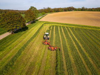 Aerial drone shot of farmer with tractor making hay on field in rural southern Germany