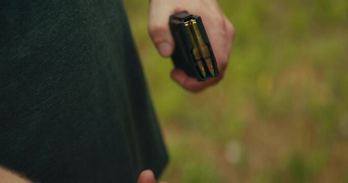 5.56 bullets being grabbed and loaded into a magazine