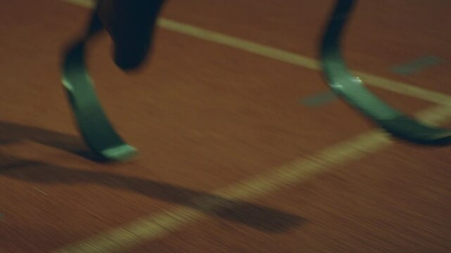 Front view of A para runner on the track running at night with prosthetics in focus