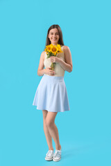 Young happy woman with bouquet of beautiful sunflowers on blue background