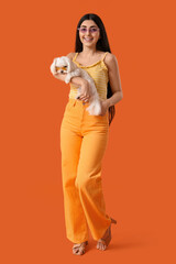 Young happy woman in sunglasses with her adorable Bolognese dog on orange background