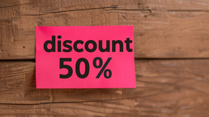 Obraz premium Pink discount 50% sign displayed on a wooden background, perfect for sales and promotions in retail or online stores.