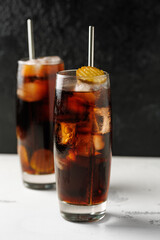 Soft drink cola with pickles and ice in a glass.
