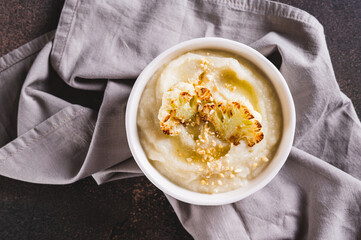 Close up of homemade creamy cauliflower soup in a bowl on the table top view
