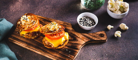 Keto burgers on cauliflower fritters with cutlet, tomato and cheese on a board web banner