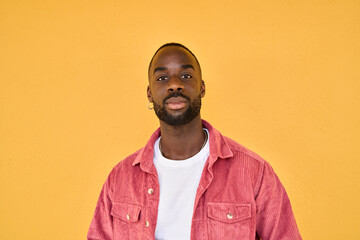 Portrait of confident young adult African American man hipster standing isolated on yellow wall....