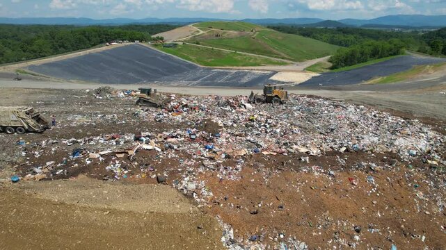 VIRGINIA - 7.5.2024 - Great aerial view circling counterclockwise around bulldozers at a garbage dump in Virginia.