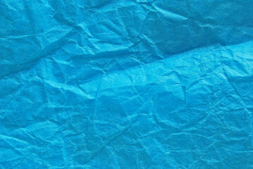 A sheet of wrinkled glossy blue paper texture as background