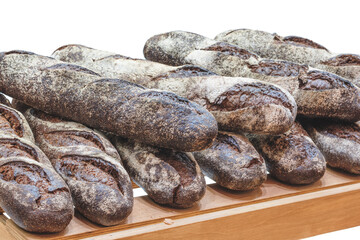 A row of brown bread loaves sit on a wooden shelf. The bread is crusty and has a slightly sweet flavor. Concept of warmth and comfort, as the bread is a staple food in many cultures