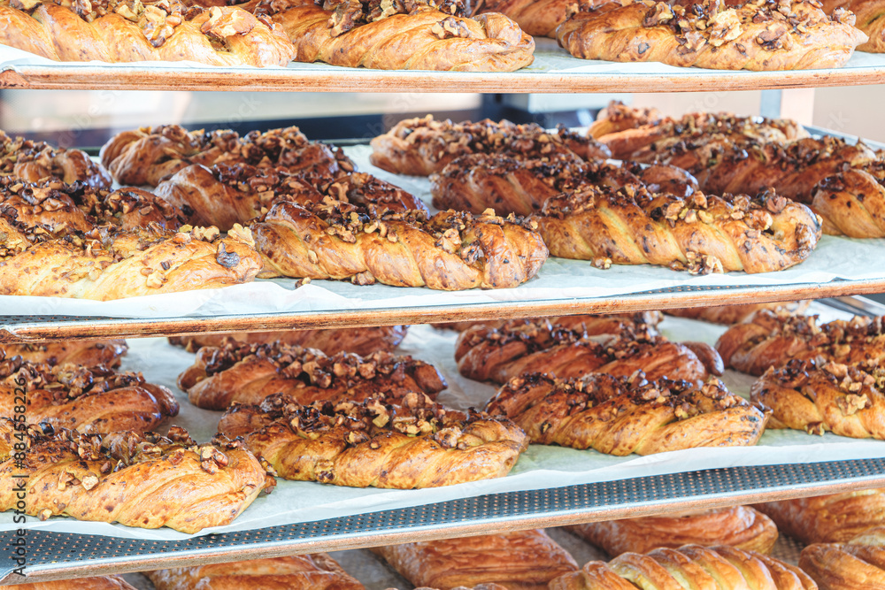 Poster a stack of pastries with walnuts on top. the pastries are on a conveyor belt and are ready to be sol