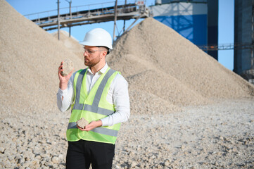 A worker in a helmet stands at a stone crushing plant
