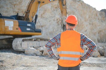 Worker in hardhat standing in stone quarry