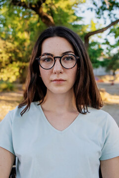 Young woman with glasses looking at camera in a park