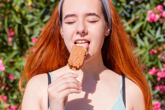 Young woman enjoys a chocolate ice cream on sunny day