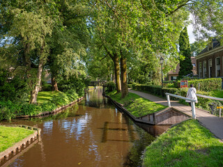 visitor walks on wooden bridge next to canal in dutch village of giethoorn