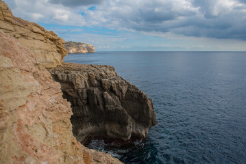 High Cliffs of Malta Island with a view of the sea on which a boat is sailing