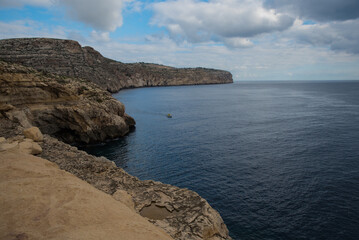 High Cliffs of Malta Island with a view of the sea on which a boat is sailing