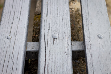 Horizontal color photo, wooden cracked slats connected by metal fasteners close together on gray concrete background.