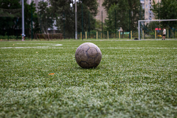 Old dirty ball on green soccer field.
Team sport, football match at the stadium