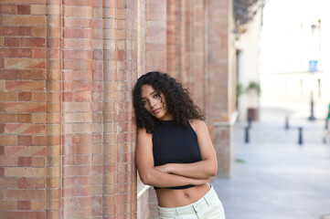 beautiful Latin woman with black eyes and brunette with long curly hair leaning on her side with...