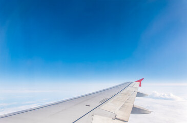 Fototapeta premium View from the airplane window at a beautiful cloudy sky and the airplane wing