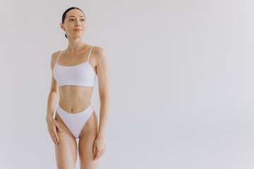 Portrait of beautiful woman with slim body in underwear posing in the white studio background with copy space, mock-up