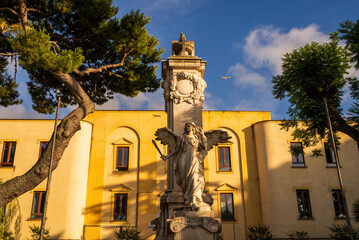 Elegant angel statue in front of a historic building, captured on a sunny day. Mors Immortalis monument, Piazza della Vittoria © Arpan