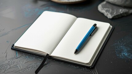 Blank bullet journal and blue pen on black desk
