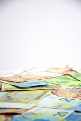 A close-up image of euro banknotes scattered on a white background, with a shallow depth of field and a blurry background