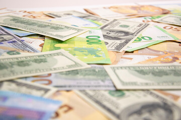 A close-up shot of a pile of US dollars and Euros on a white surface, with a focus on the top of the pile