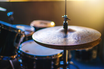 Drum kit cymbals in dimly lit music studio, texture and details of the instruments. 