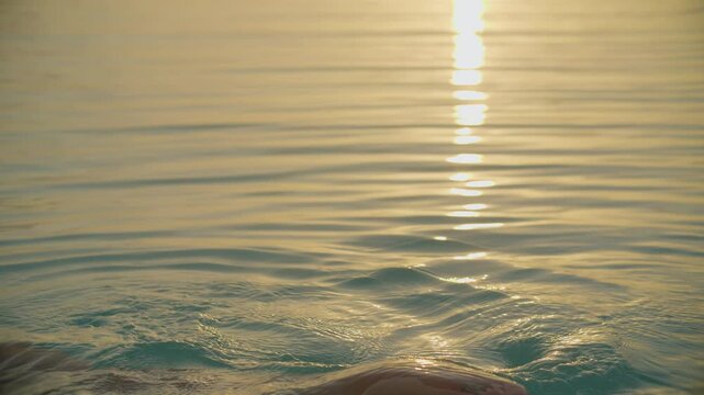 amanecer en la laguna de bacalar cona persona tocando el agua