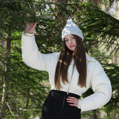 Teenage girl stands proudly in winter pine forest. She's brunette, looking absolutely radiant as...