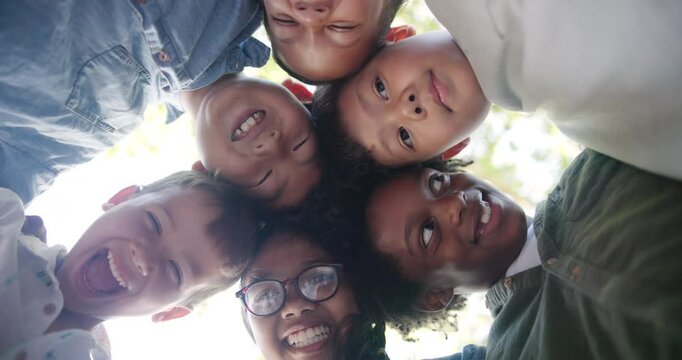 Kids, support and friends with huddle in outdoor park for circle, bonding or development. Low angle, diversity and young children with solidarity for community, happiness or connection in playground
