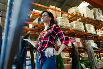 Thoughtful female storekeeper looking for tedious goods in building materials warehouse